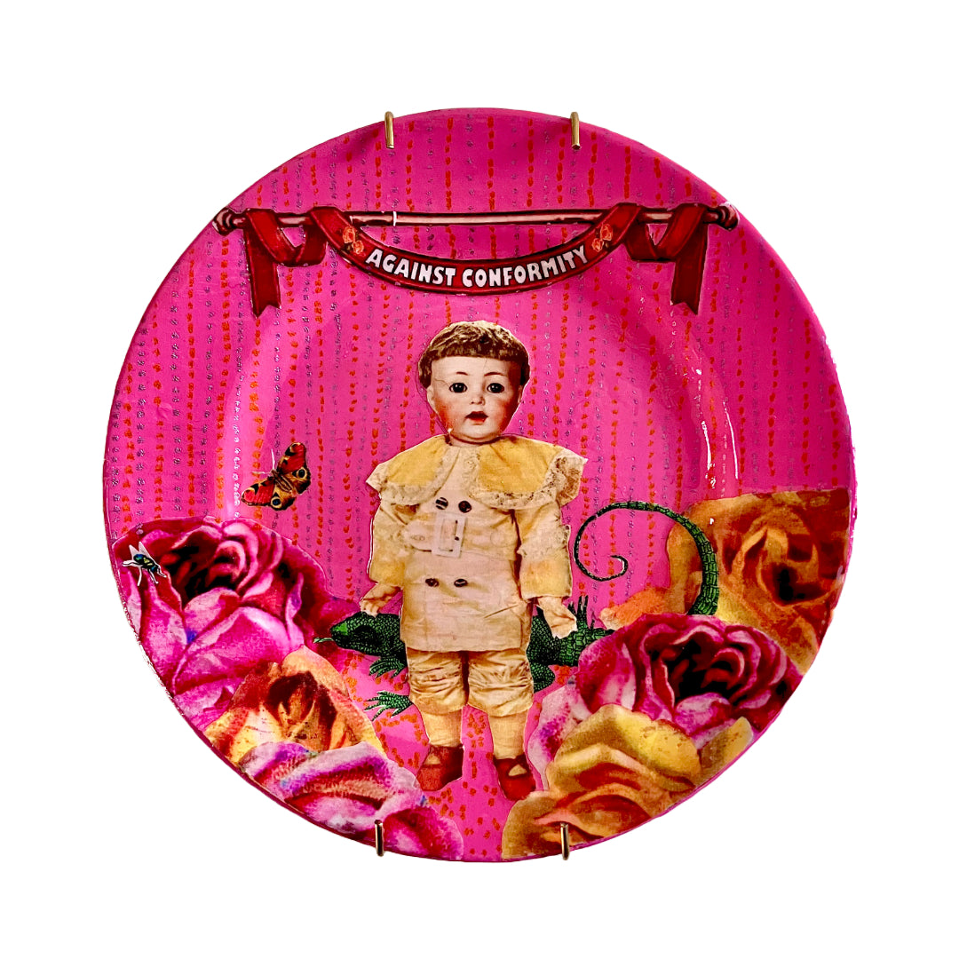 Against Conformity Wall Plate by House of Frisson, featuring a collage of a kitsch vintage male doll, surrounded by roses, a lizard, and a moth, on a pink coloured background.