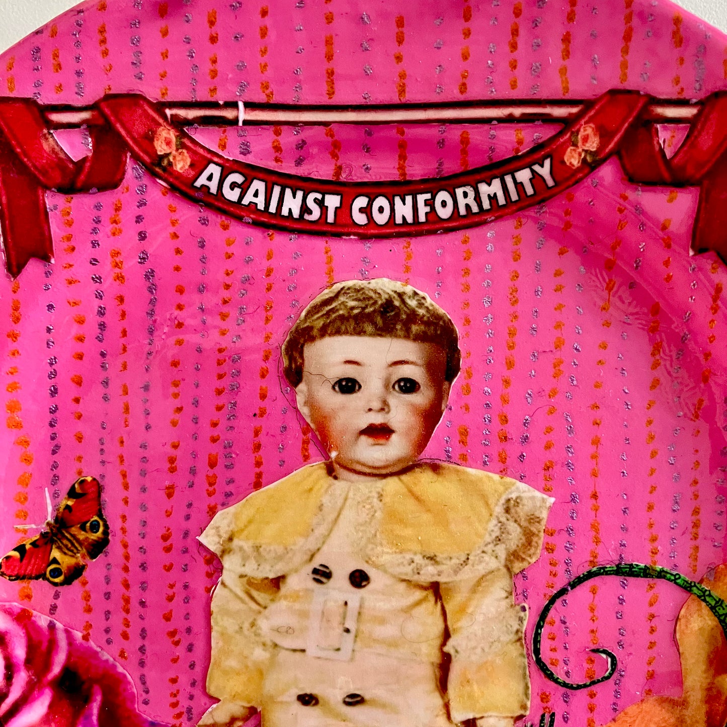 Against Conformity Wall Plate by House of Frisson, closeup detail of the collage showing a kitsch vintage male doll, a moth, on a pink coloured background.