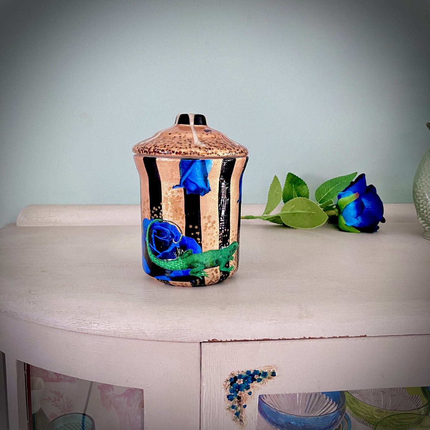 Gold Upcycled Jar by House of Frisson, featuring a collage of blue roses, bones, and a lizard, on a background of gold and black stripes. 