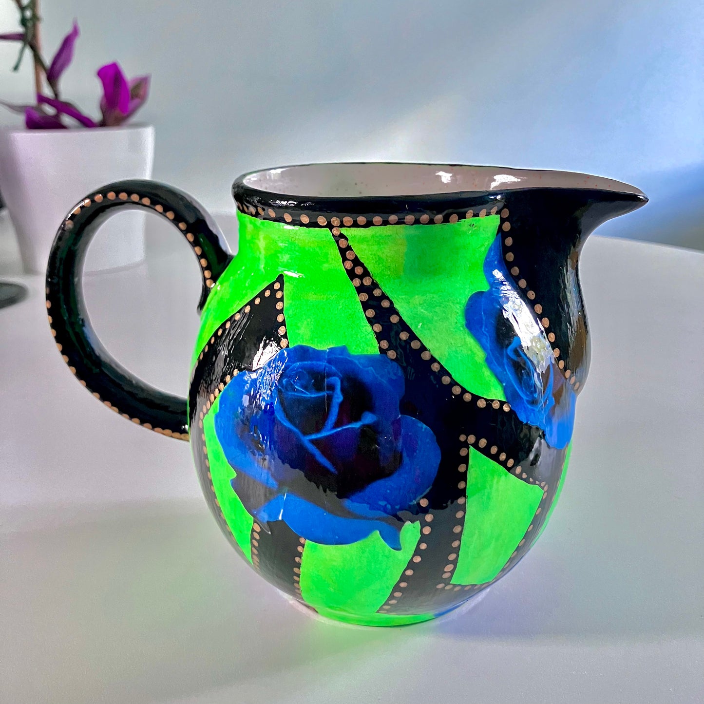 Neon Green upcycled Pitcher/Vase by House of Frisson, featuring some graphics in black and blue roses, beautifully contrasting with the bright green background.