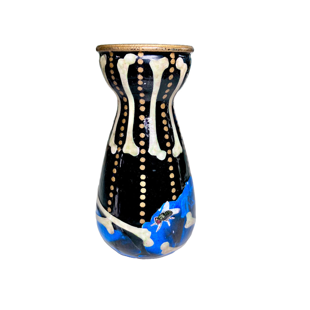 Black Upcycled Glass Bottle/ Vase by House of Frisson, featuring a collage of human bones and blue roses against a black background with some golden dots accent. Quirky and cool.