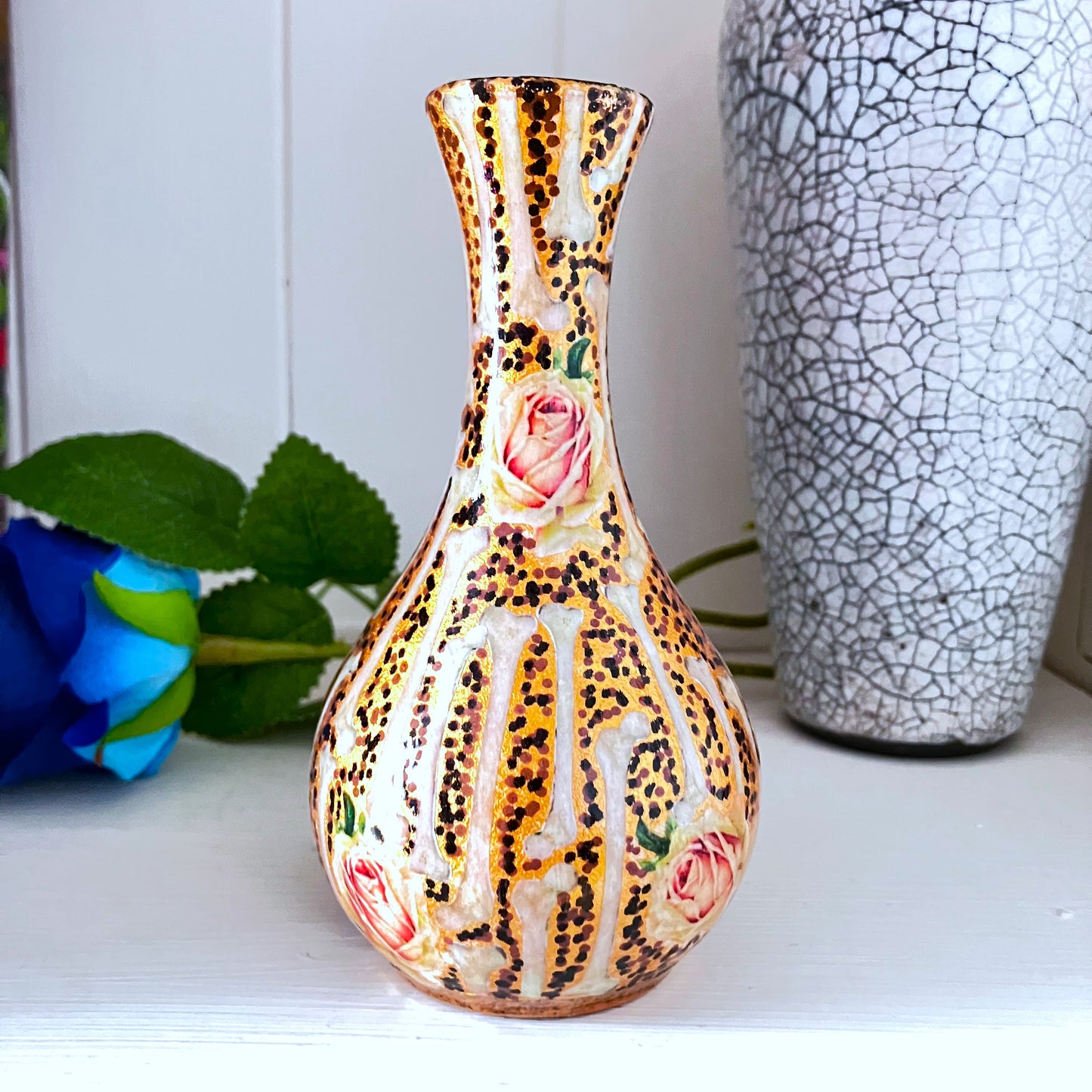 Upcycled ceramic flower vase featuring a collage design of bones and roses in a bronze cage that will add a unique touch to any room. 