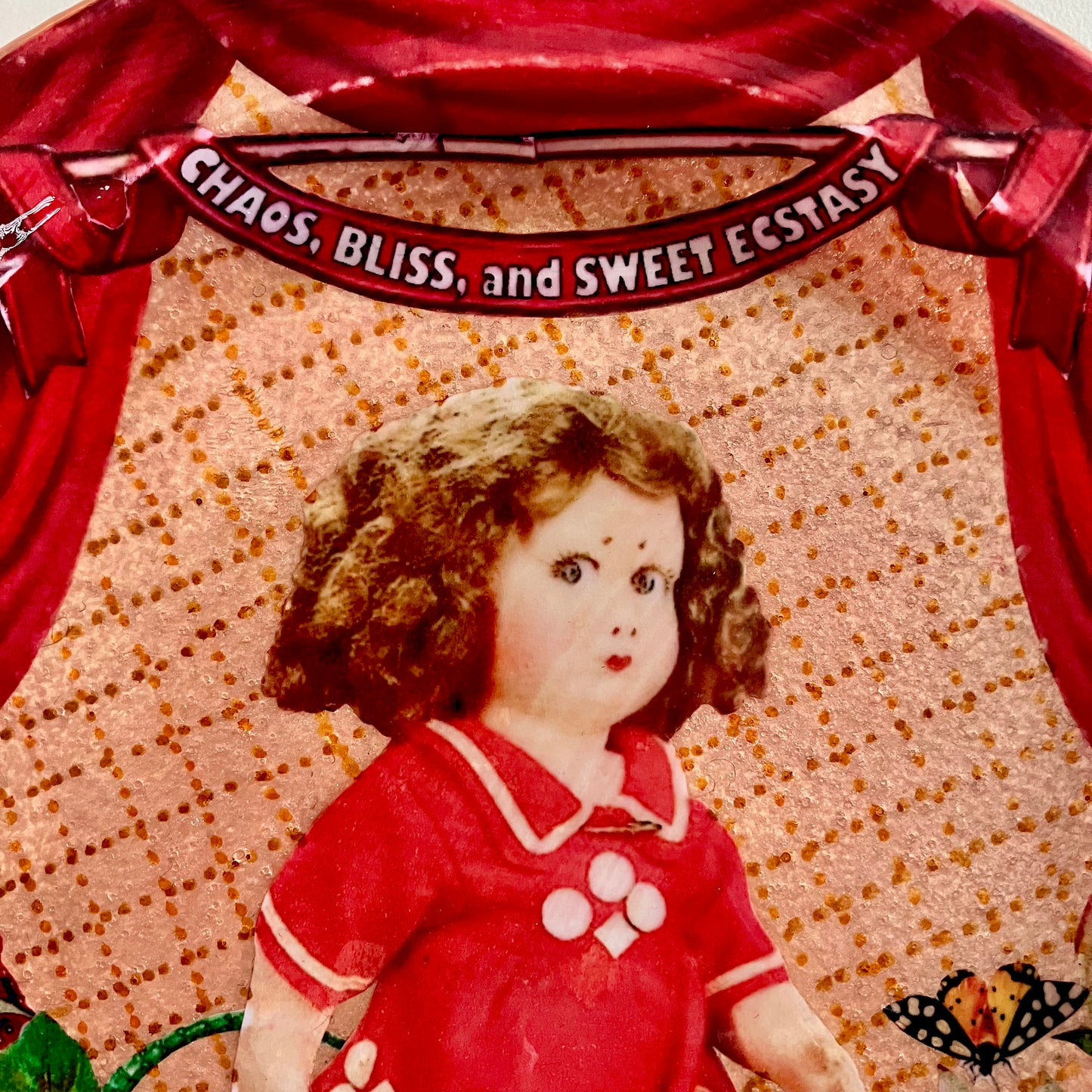 Chaos, Bliss, and Sweet Ecstasy Wall Plate by House of Frisson, closeup detail showing a kitsch vintage doll, a moth, on a blush coloured background.