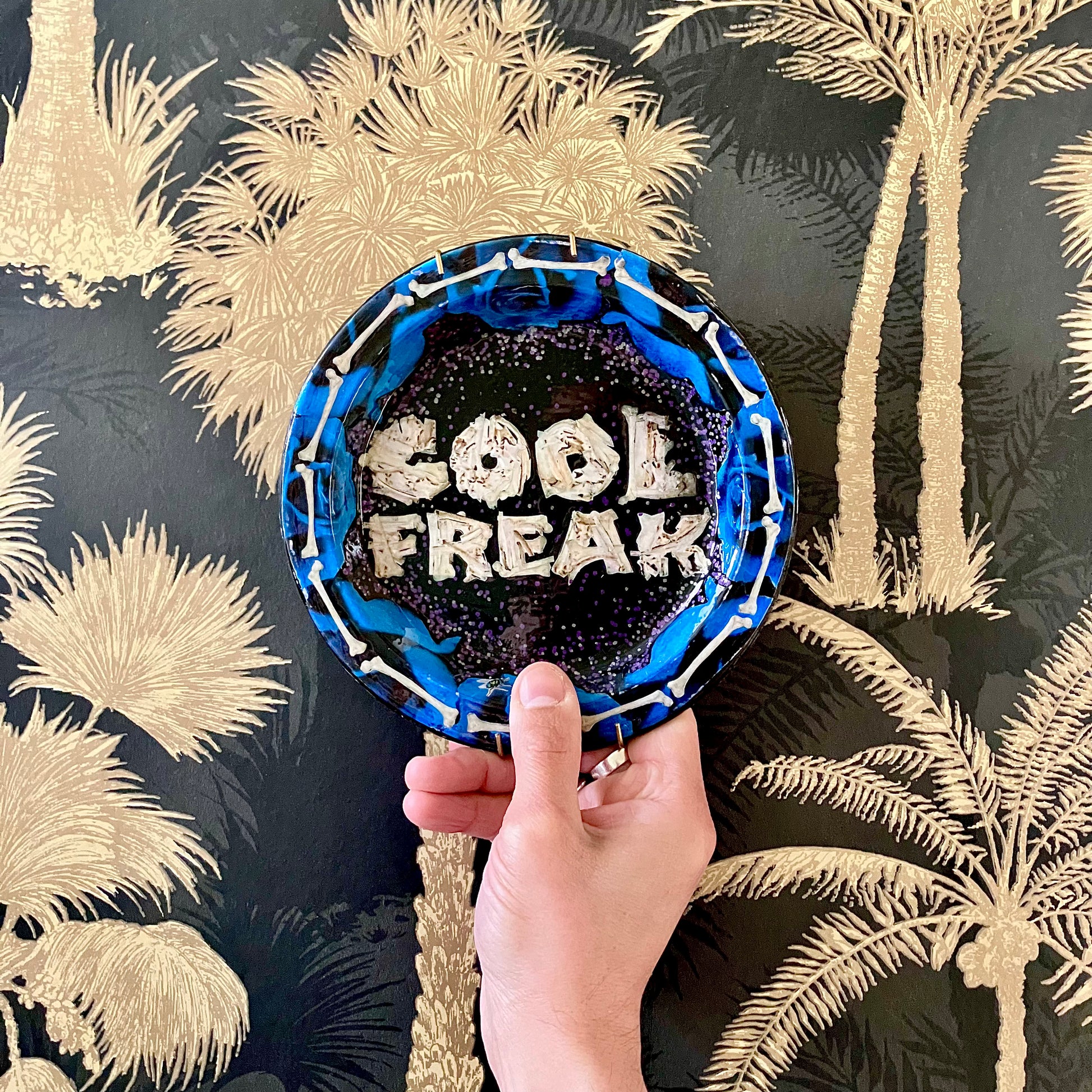 "Cool Freak" Wall Plate by House of Frisson lifestyle photo holding the plate against a wallpaper.
