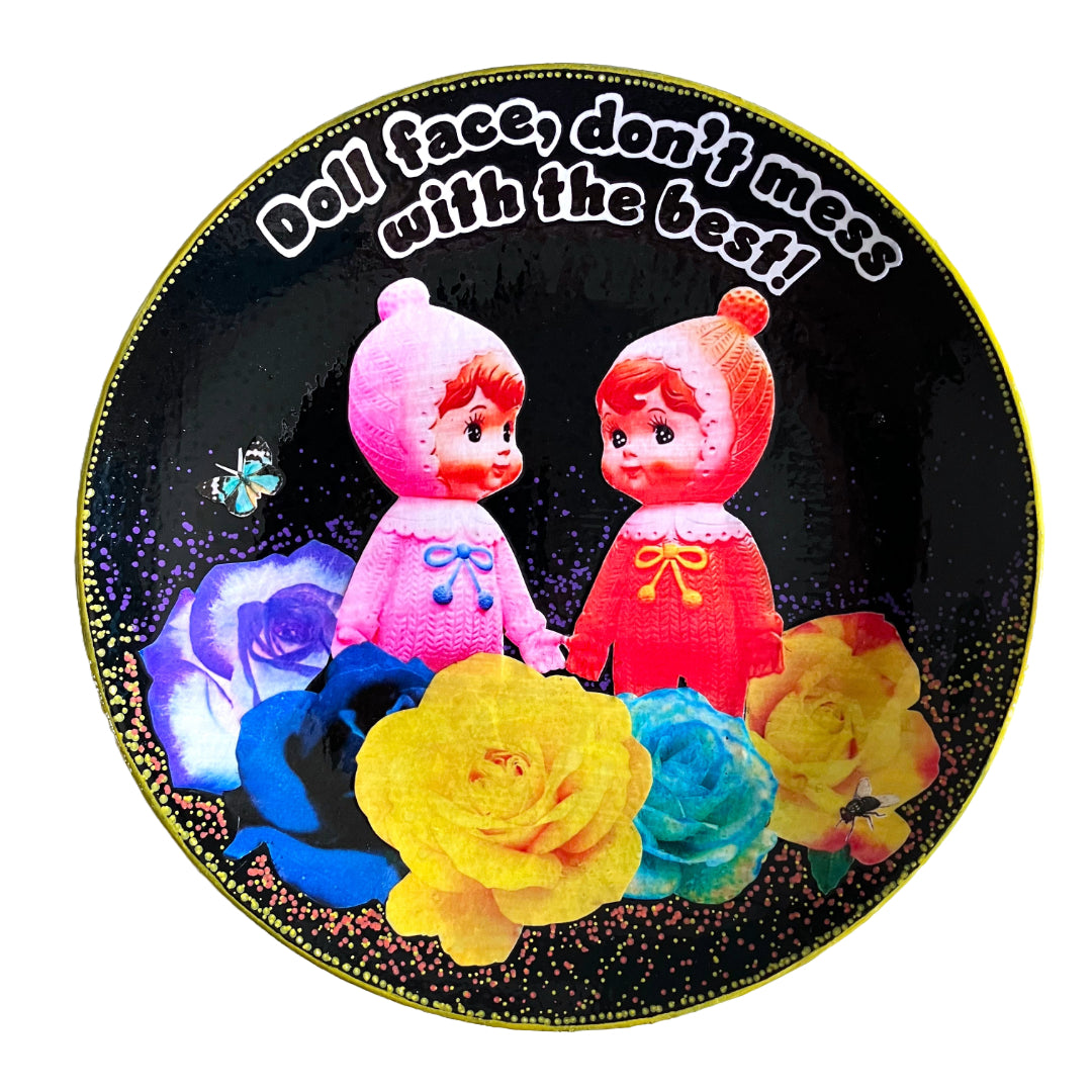 Black Upcycled Wall Plate featuring two vintage rubber dolls, surrounded by colourful roses, and a cheeky quote.