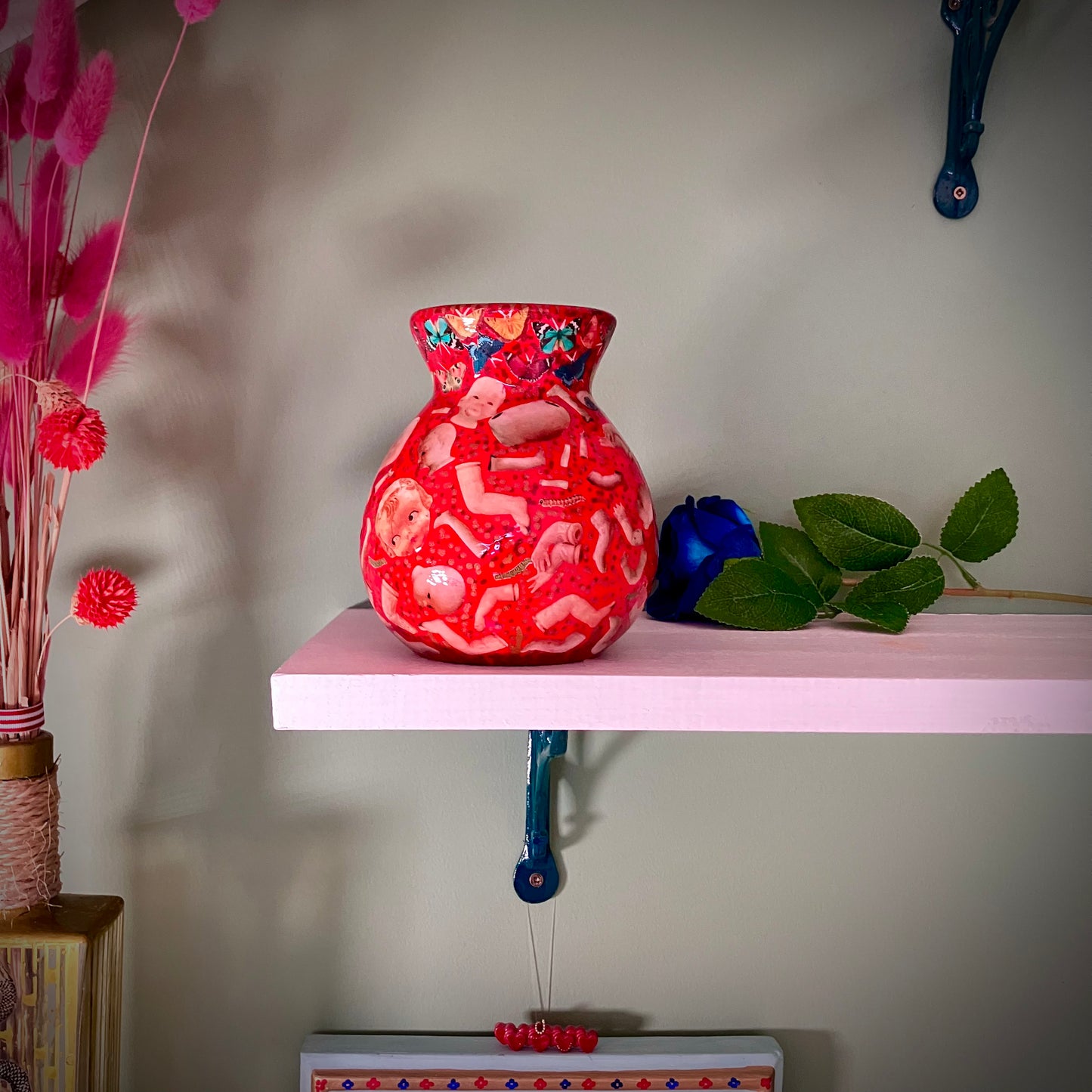 Red upcycled flower vase by House of Frisson, featuring a collage of vintage doll parts and moths.