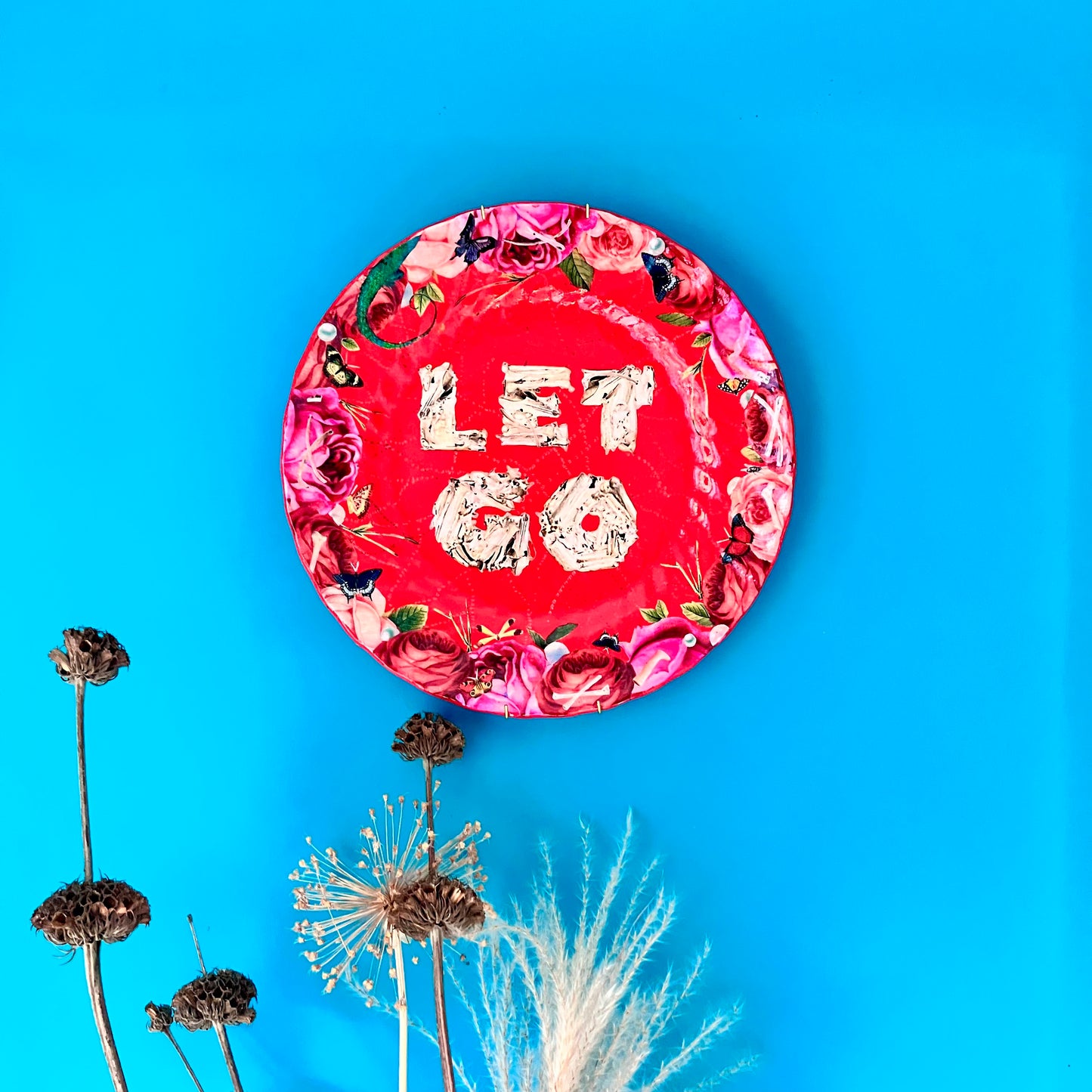 "Let Go" Wall Plate by House of Frisson hanging on a blue wall.