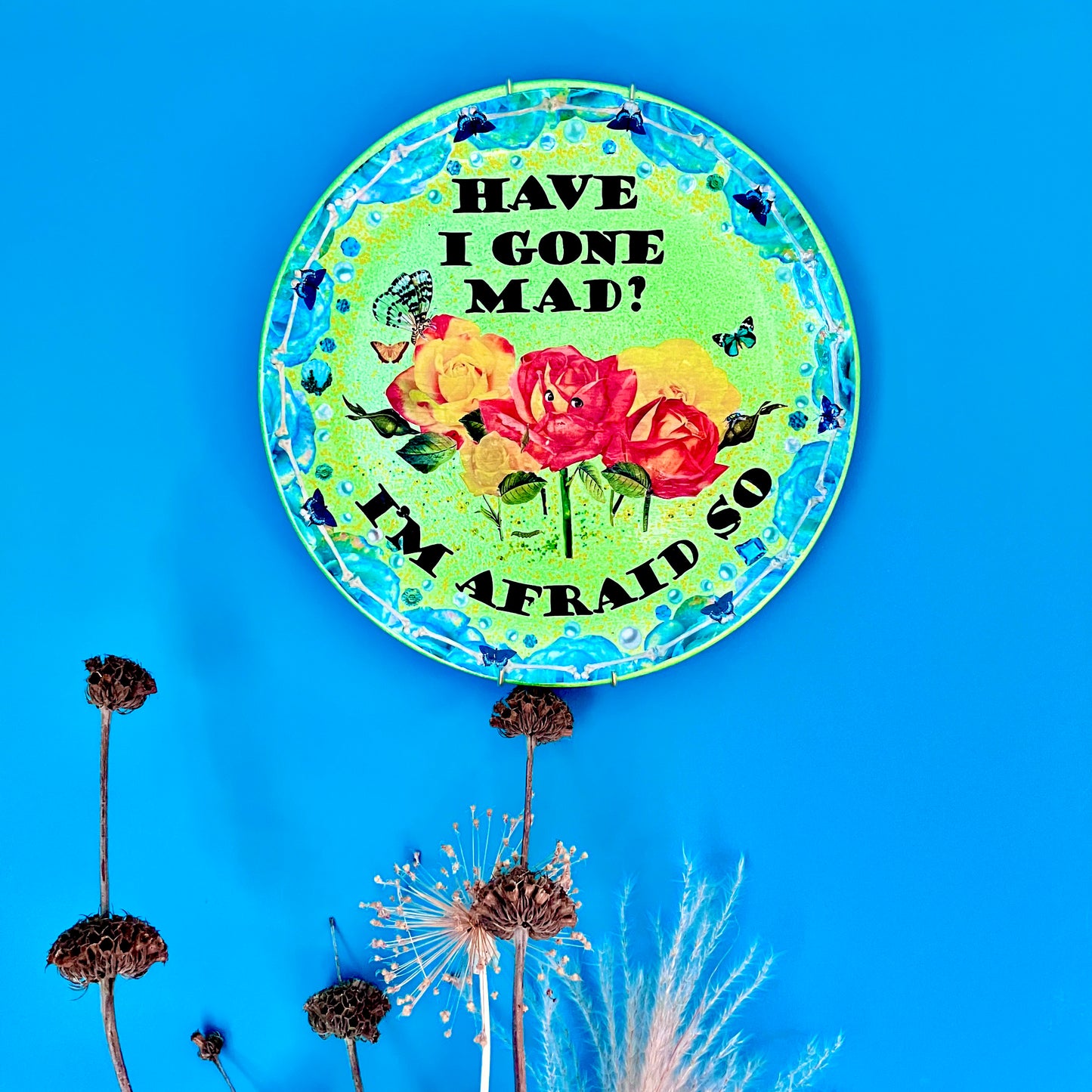 "Have I Gone Mad? I'm Afraid So" Wall Plate by House of Frisson hanging on a blue wall.