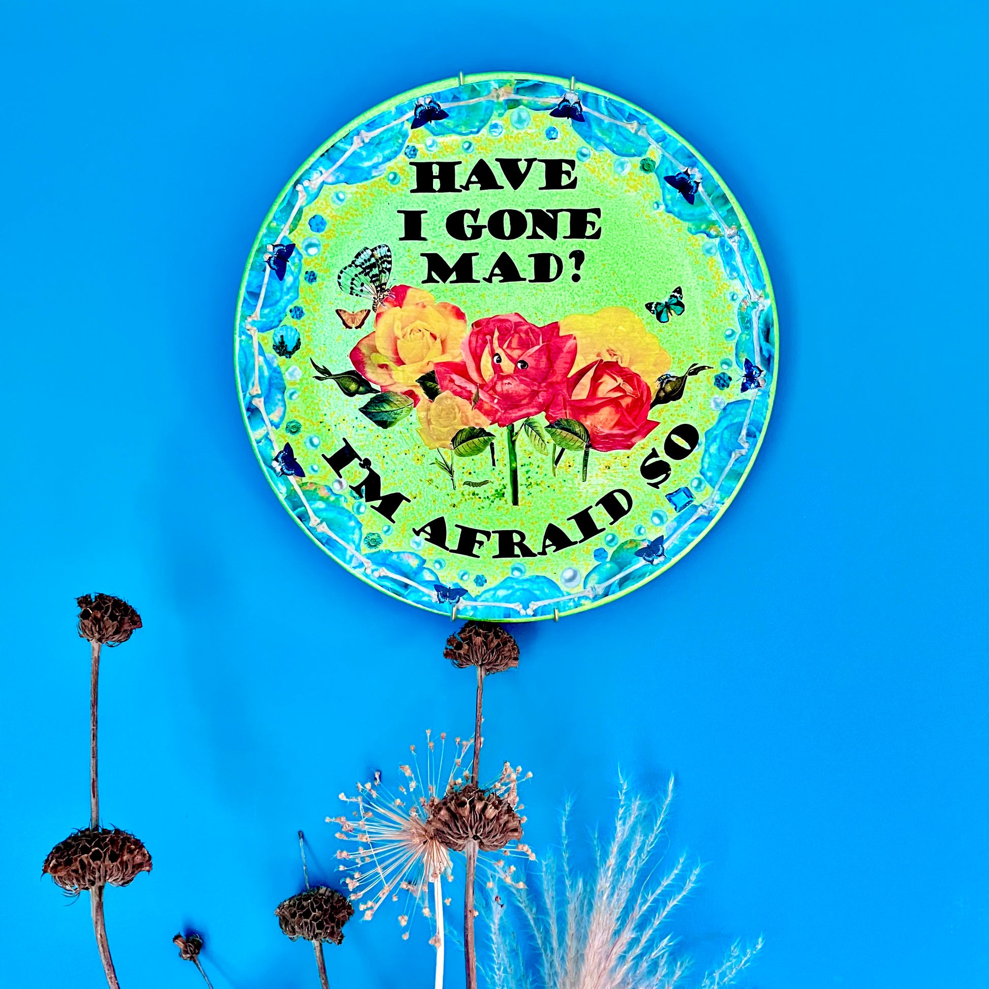 "Have I Gone Mad? I'm Afraid So" Wall Plate by House of Frisson hanging on a blue wall.