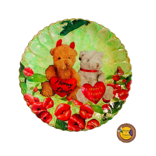 "Horny Devil. I Don't Think So" Wall Plate by House of Frisson, featuring a collage of two teddy bears holding hearts with messages, among lip-shaped flowers, on a green background.