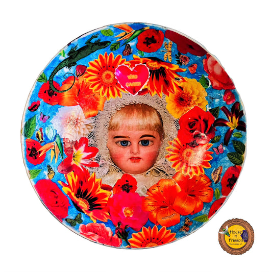 "Who Cares" Wall Plate by House of Frisson, featuring a vintage doll surrounded by flowers, moths, and a lizard, on a blue background.