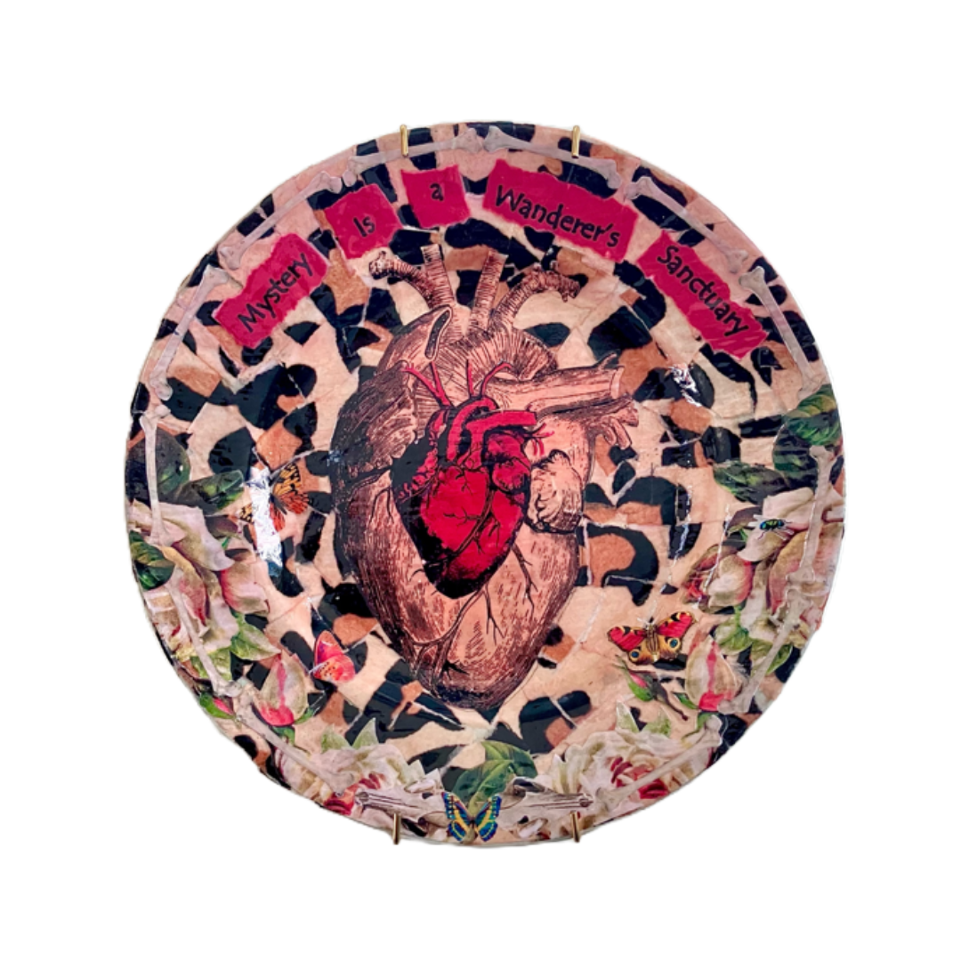 Mystery is a Wanderer's Sanctuary Wall Plate by House of Frisson, featuring a collage artwork of two anatomical human heart illustrations, framed by white roses, moths, and bones, on a background of beige leopard print.