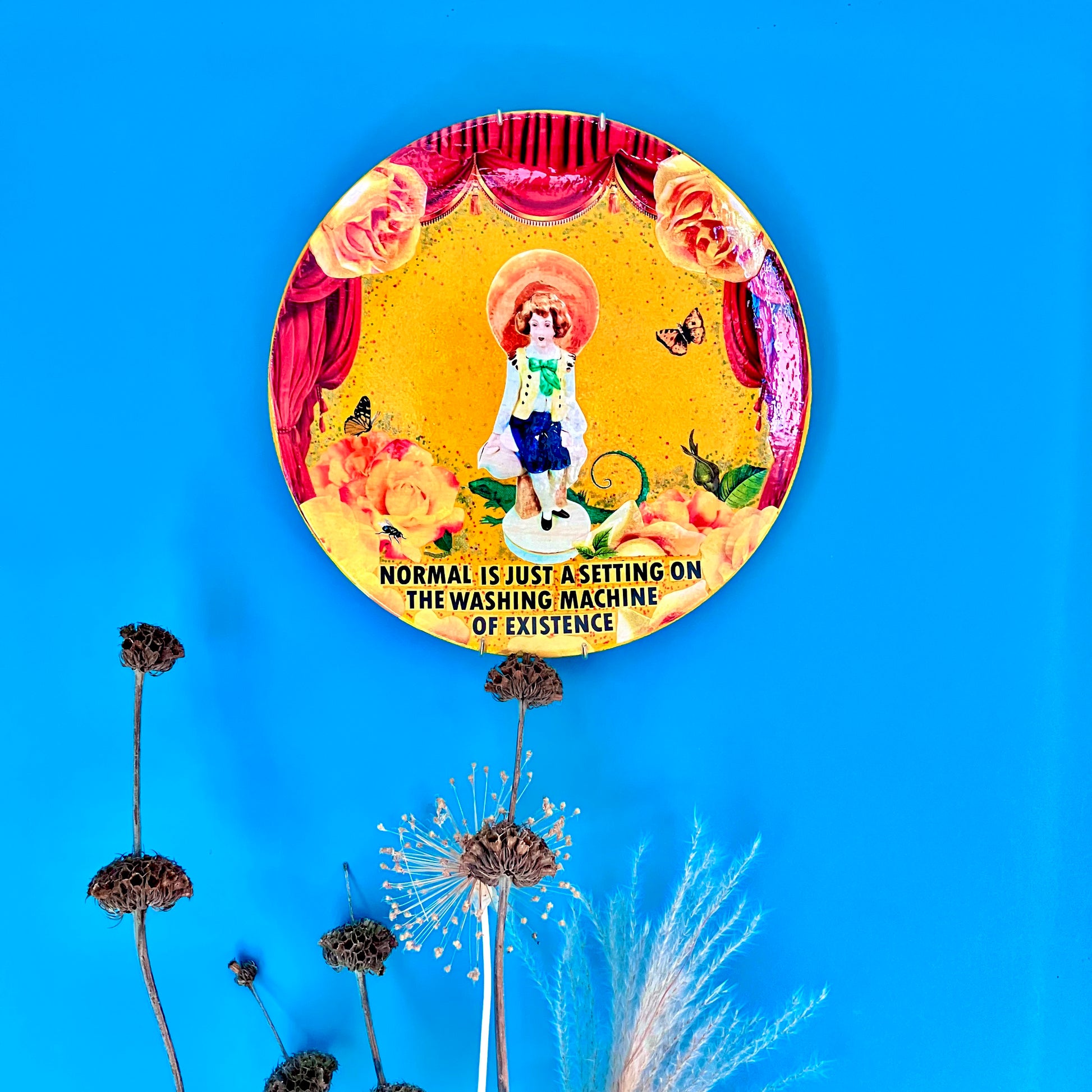 "Normal Is Just A Setting On The Washing Machine Of Existence" Wall Plate by House of Frisson, hanging on a blue wall.