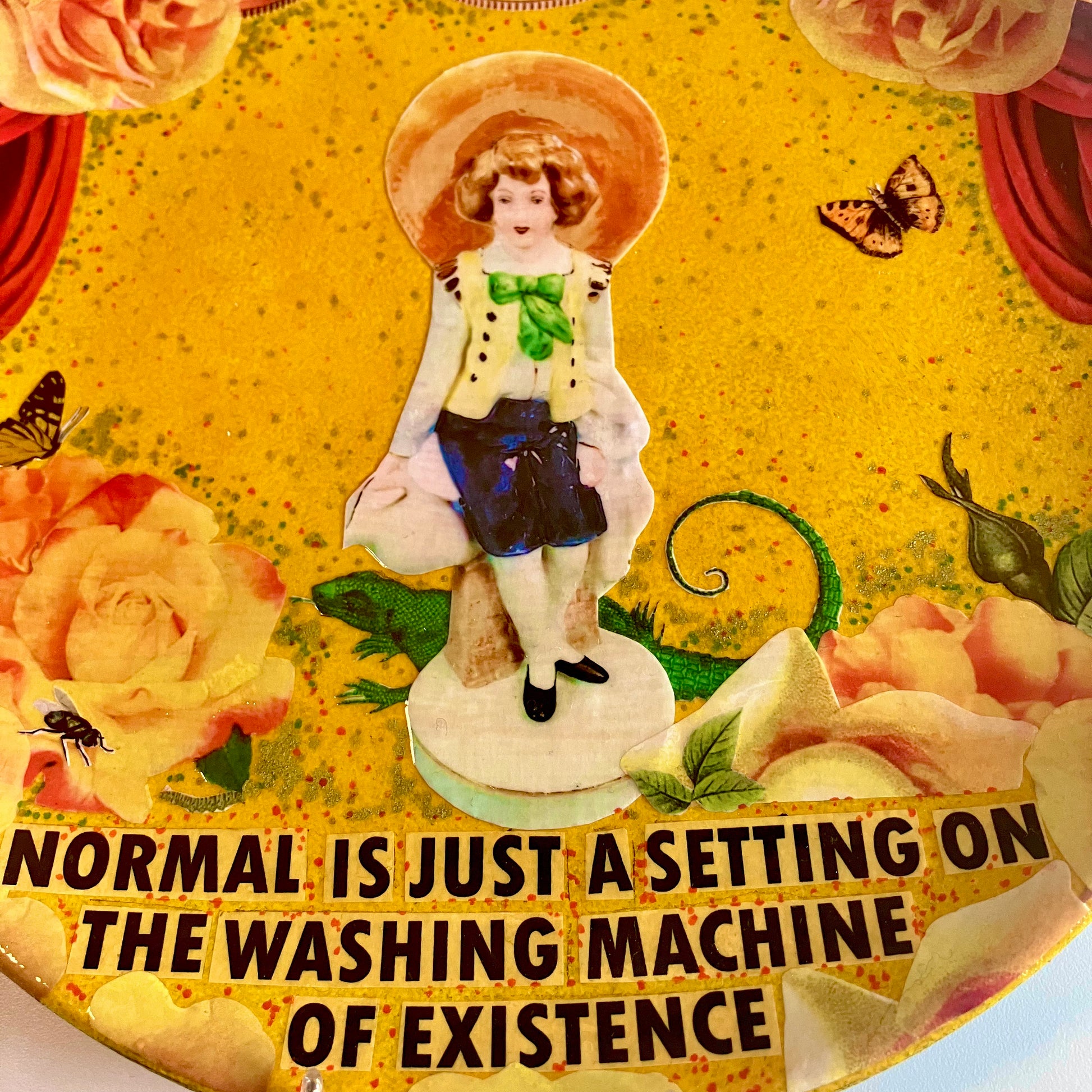 "Normal Is Just A Setting On The Washing Machine Of Existence" Wall Plate by House of Frisson, closeup detail of the collage showing a porcelain figure surrounded by roses.