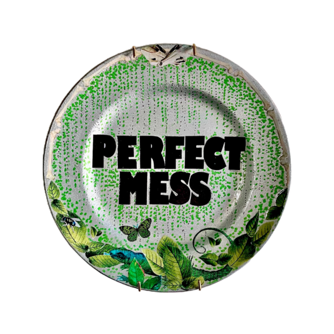 "Perfect Mess" Wall Plate by House of Frisson, featuring a collage artwork with the words Perfect Mess, framed with green leaves, moths, and bones, on a silver background.