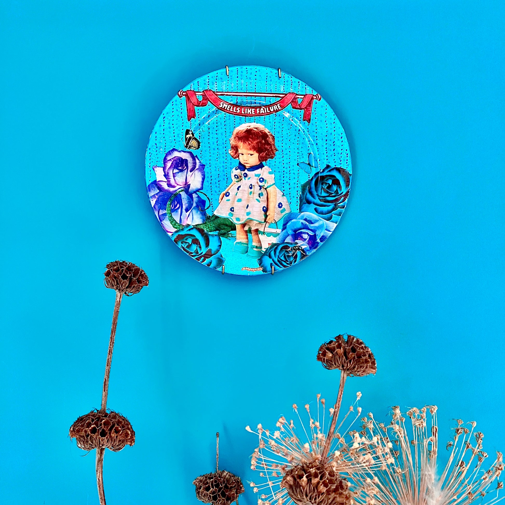 "Smells Like Failure" Wall Plate by House of Frisson, hanging on a blue wall.