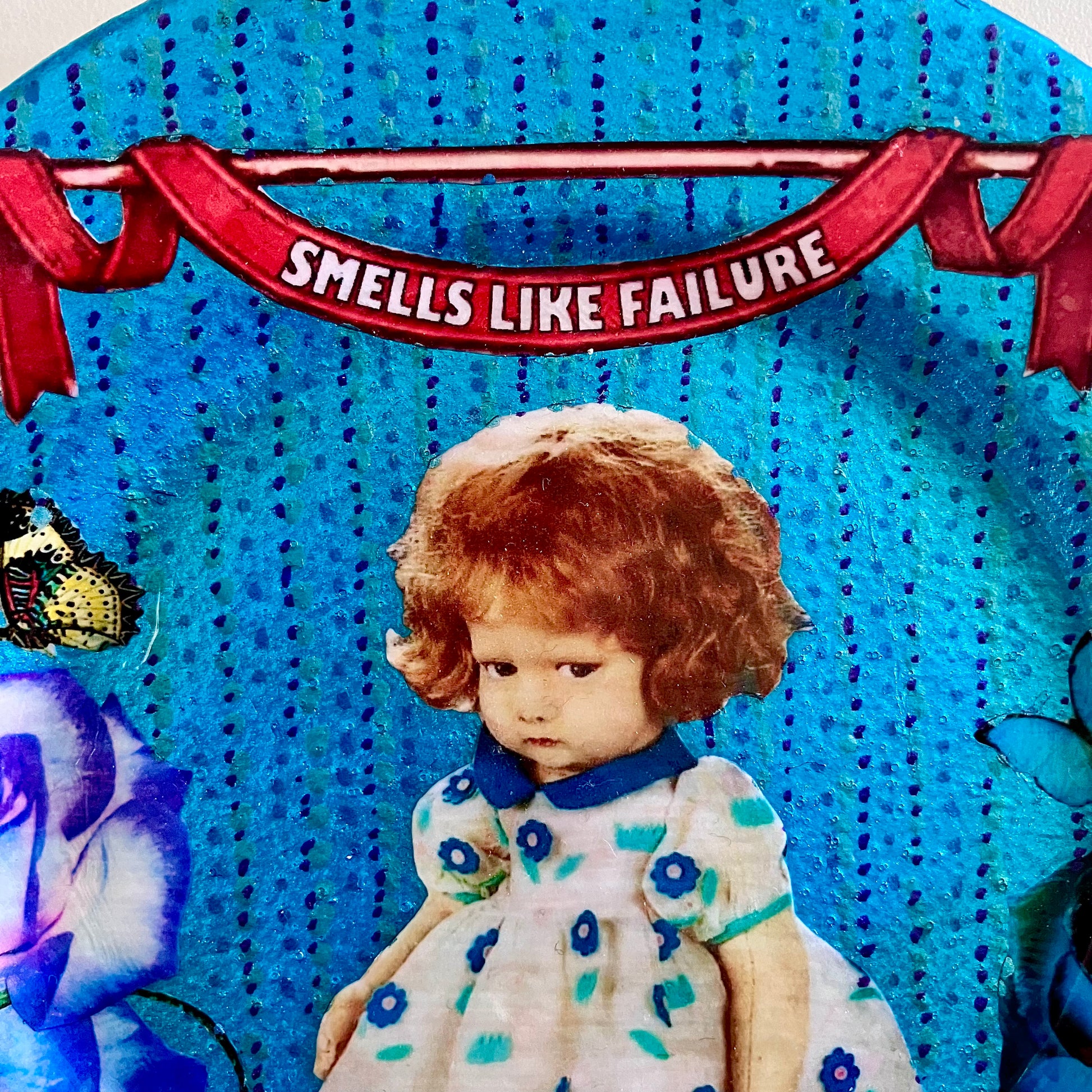 "Smells Like Failure" Wall Plate by House of Frisson, closeup detail showing a vintage doll and blue roses.