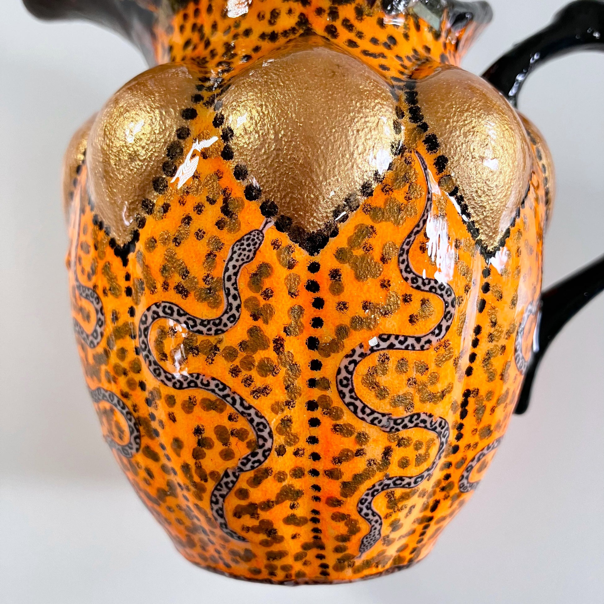 Orange and black upcycled jug/vase by House of Frisson, featuring a collage of snakes against an orange background with black accent. Details.