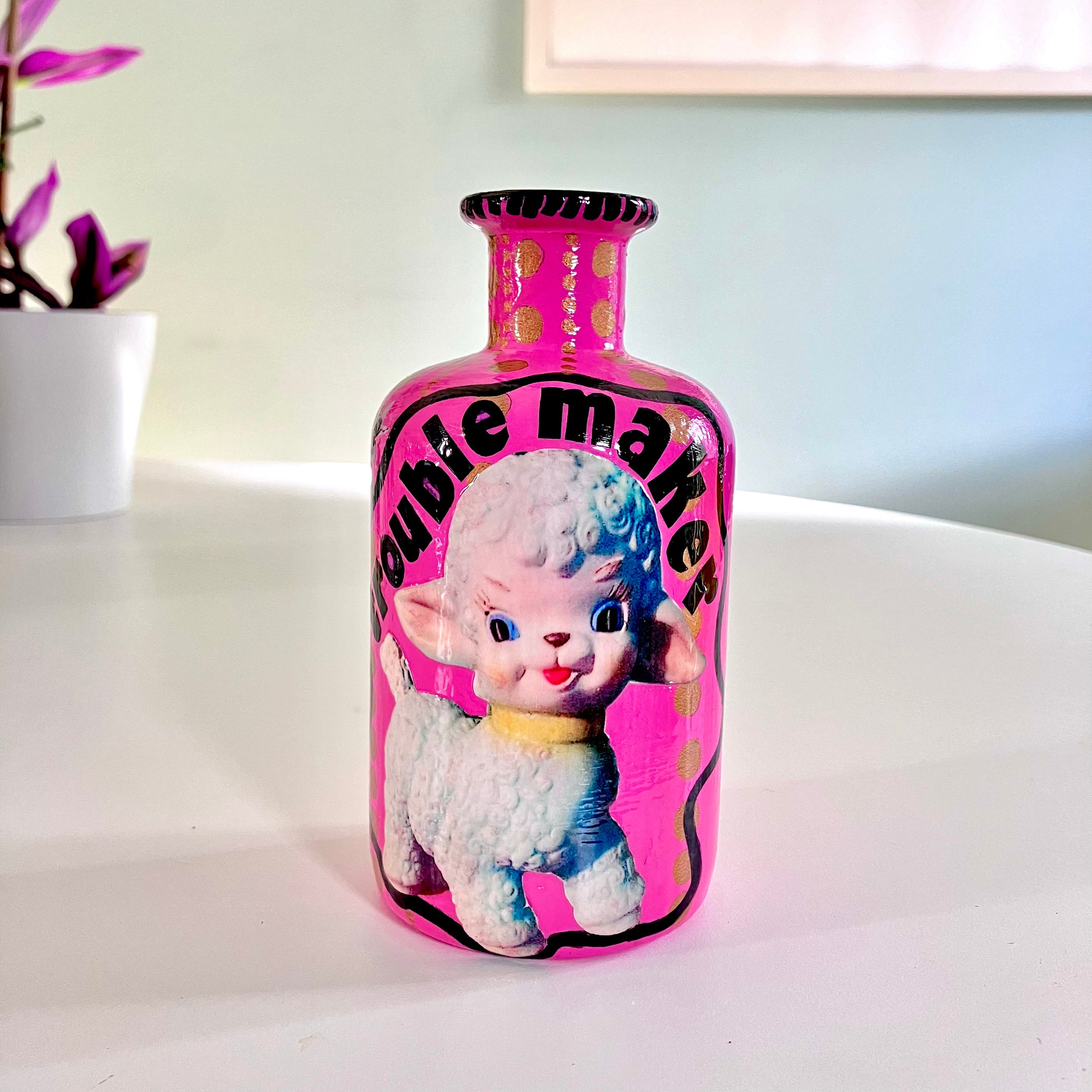 Bright Pink Upcycled Glass Bottle by House of Frisson, featuring an image of a kitsch squeaky lamb toy and some golden dots accent.