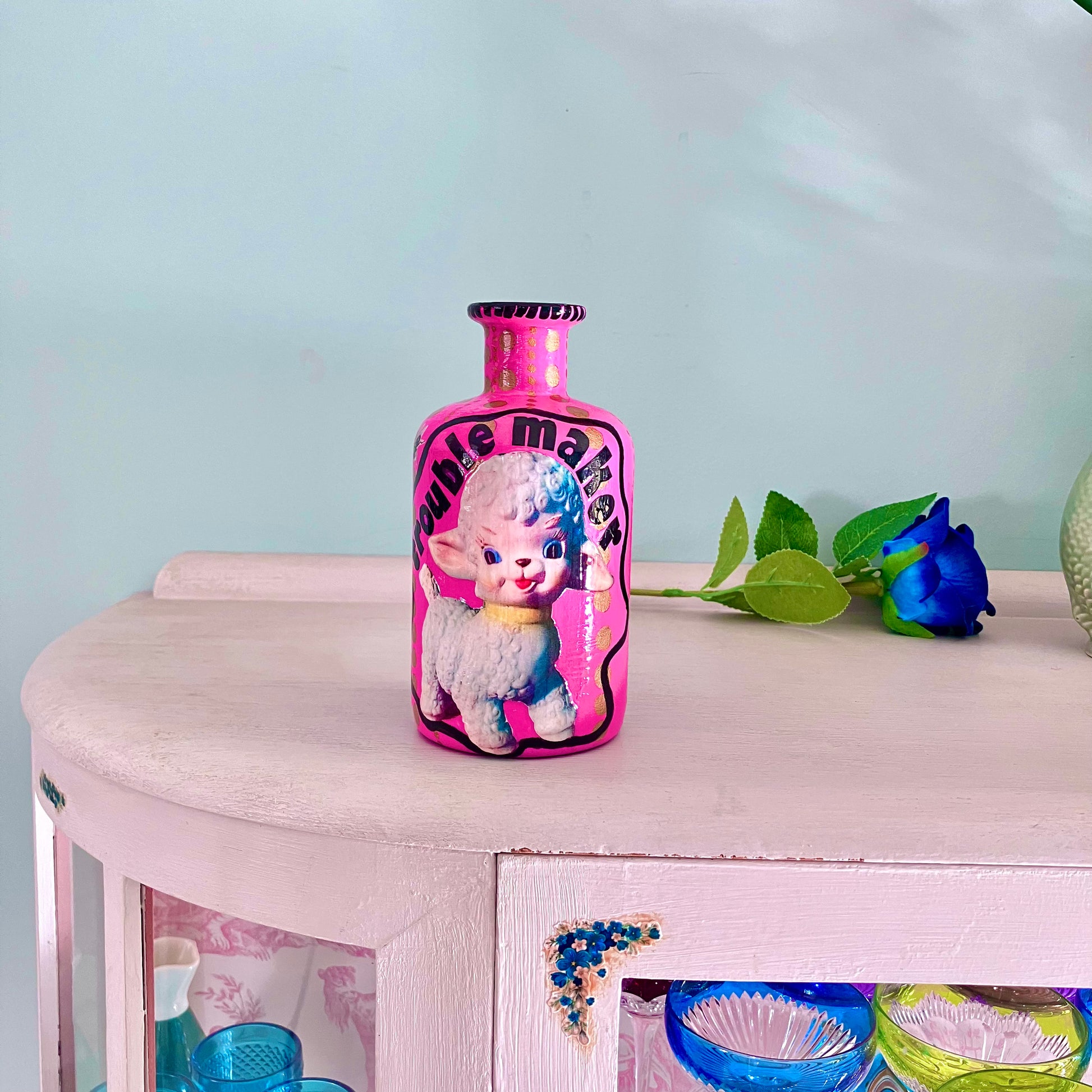 Bright Pink Upcycled Glass Bottle by House of Frisson, featuring an image of a kitsch squeaky lamb toy and some golden dots accent.