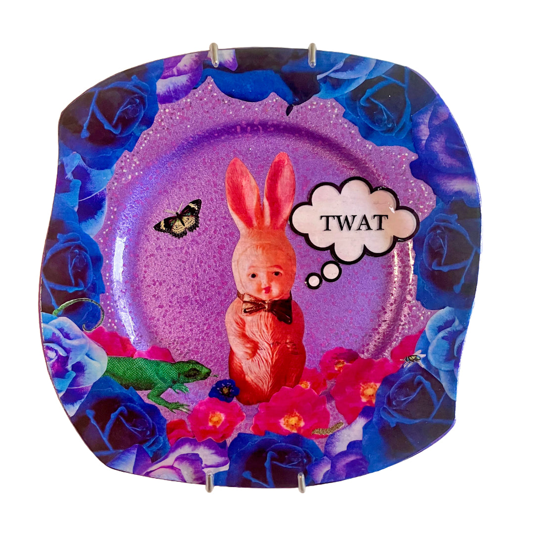 "Twat" Wall Plate by House of Frisson, featuring a collage of a kitsch pink bunny set against a purple background and framed by blue roses.