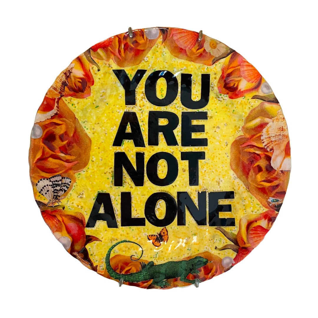 "You Are Not Alone" one-of-a-kind collage artwork Wall Plate by House of Frisson. Featuring the words "You Are Not Alone" framed by roses, pearls, and moths, on a yellow background.