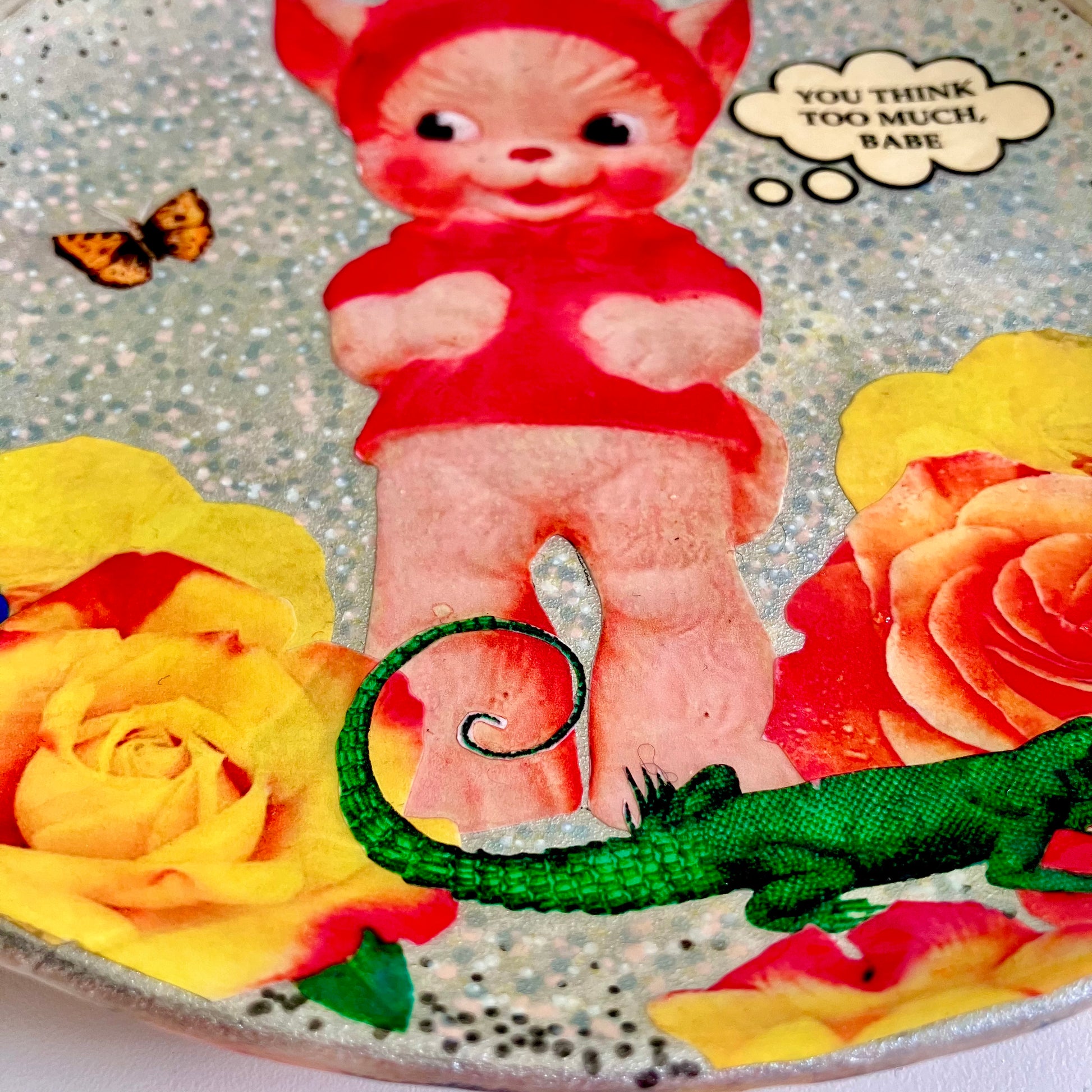 "You Think Too Much, Babe" Silver upcycled wall plate by House of Frisson, featuring a kitsch squeaky toy, some colourful roses and House of Frisson's creatures. Closeup details.