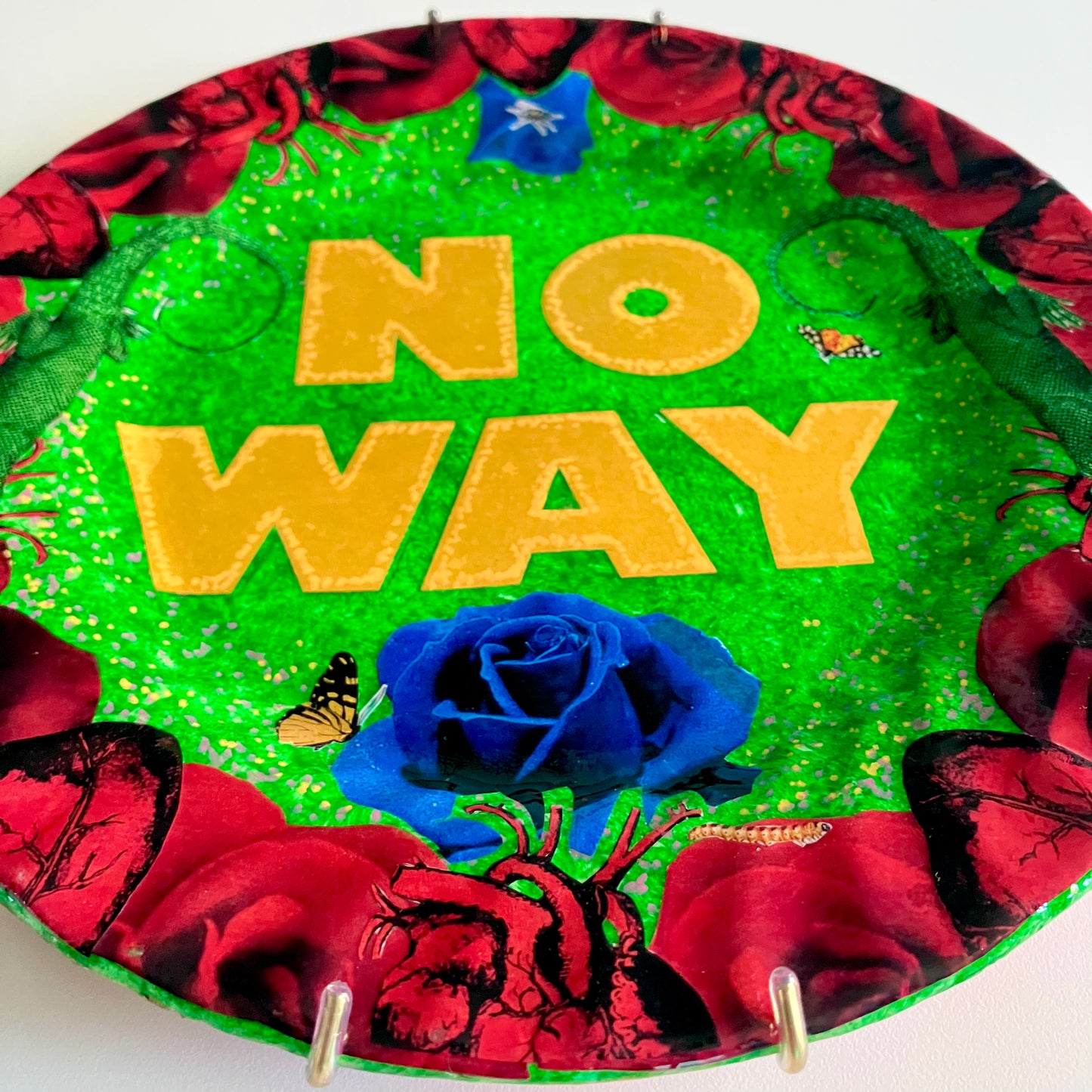 "No Way" one-of-a-kind collage artwork on upcycled wall plate by House of Frisson. Featuring the words "No Way" framed with a collage of roses, and lizards, on a green background. Closeup showing the details of the collage.