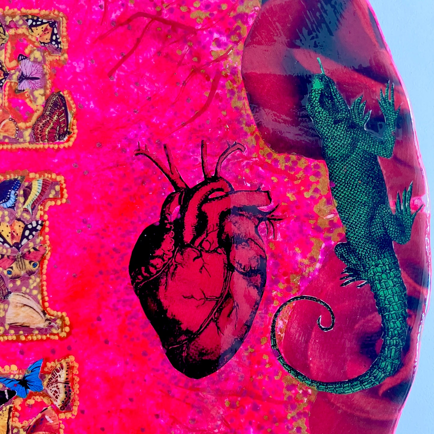 "Desire" Wall Plate by House of Frisson, featuring a collage with the word "desire" written with moths, and a frame of red roses and green lizards, on a hot pink background. Closeup detail of a lizard, roses, and an anatomical human heart illustration.