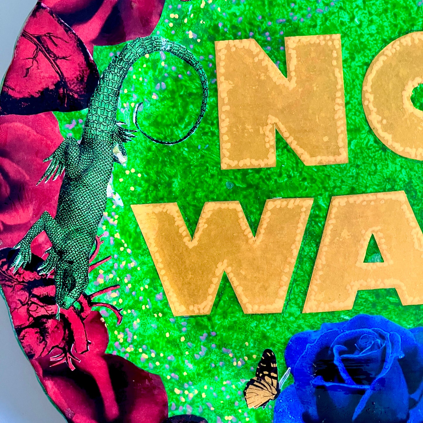 "No Way" one-of-a-kind collage artwork on upcycled wall plate by House of Frisson. Featuring the words "No Way" framed with a collage of roses, and lizards, on a green background. Closeup detail of the letters, lizard, and roses, on a green background.