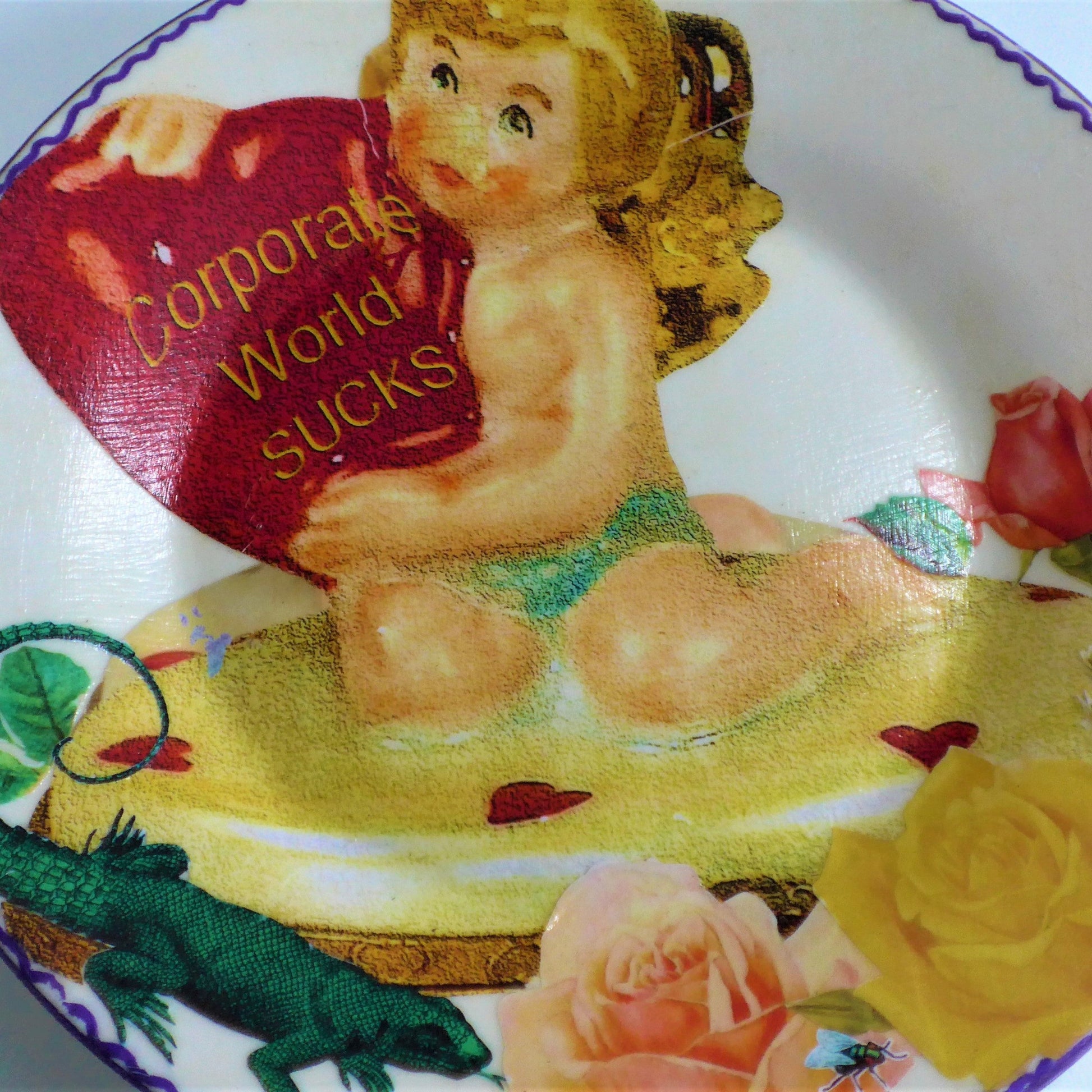 House of Frisson "Corporate World Sucks" Off White Wall Plate Front. Collage artwork featuring a kitsch angel figure holding a heart, among roses, a lizard, and a fly. Closeup detail of the angel figure.